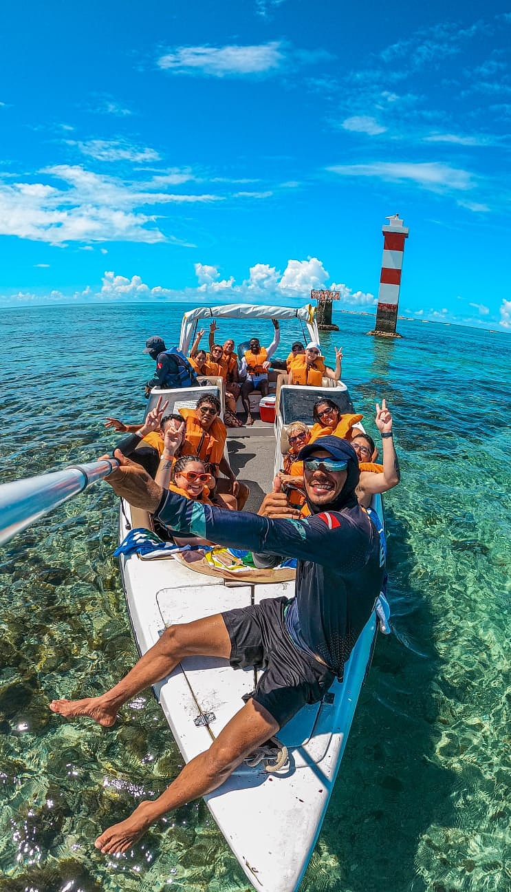 Grupo em lancha nos Parrachos com farol ao fundo