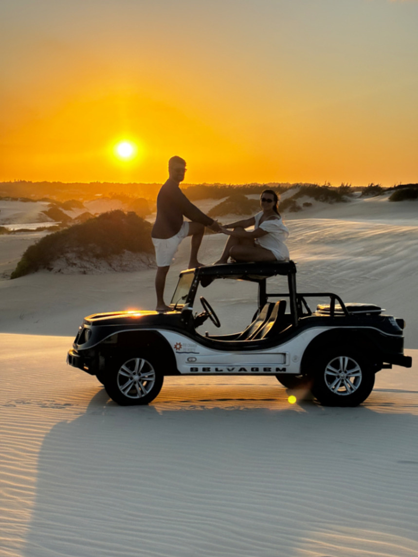 Casal em buggy nas dunas ao pôr do sol